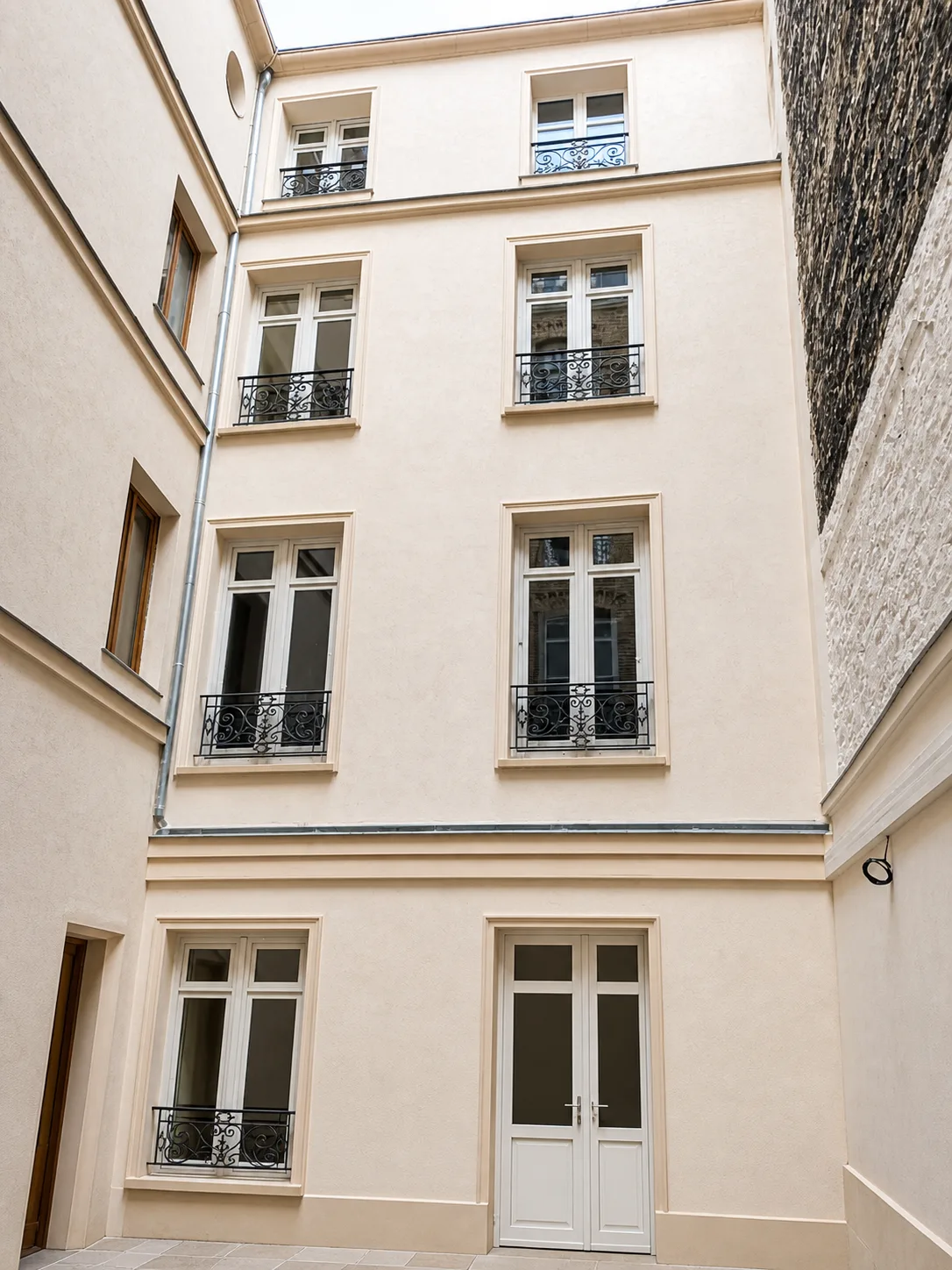 Façade de cour rénovée rue de Lévis à Paris 17e avec enduit clair, bandeaux et menuiseries reprises