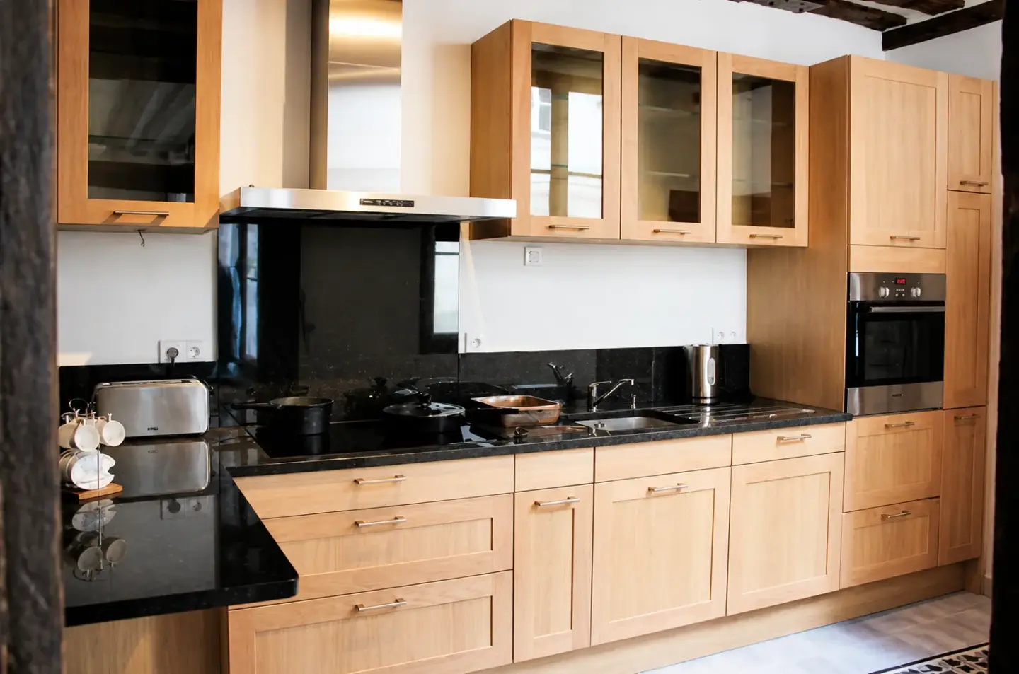 Rénovation de cuisine en bois sous combles avec poutres apparentes dans un appartement du Marais à Paris 3e