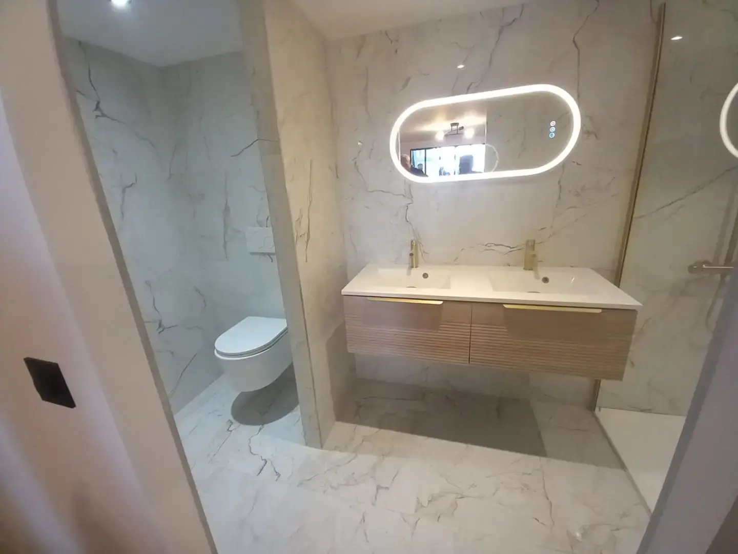Salle de bain rénovée à Paris 16e avec carrelage effet marbre, WC suspendu et meuble vasque